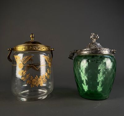 two green glass jars with gold designs and lids on a gray surface