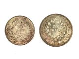 two old silver coins on a white surface