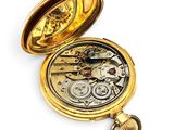 a gold pocket watch that is open on a white surface
