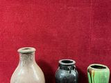 trois vases posés sur une table devant un mur rouge