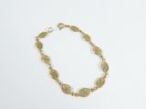 gros plan d'un bracelet en or sur une surface blanche