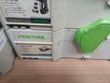 une machine à coudre verte et blanche posée sur un plancher en bois