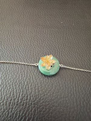 un gros plan d'un bracelet orné d'une fleur suspendue à une chaîne