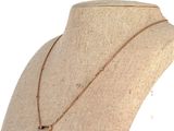 Le collier est posé sur le cou d'un mannequin, suspendu à une chaîne en or.