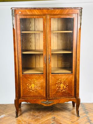 une vieille armoire en bois avec une porte vitrée, posée sur un parquet en bois massif