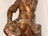 a bronze statue of a man sitting on a chair