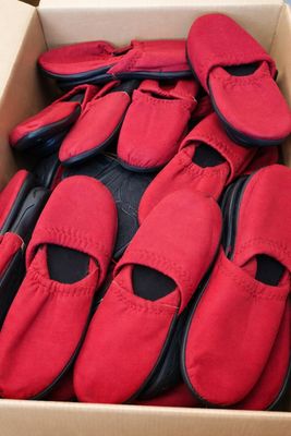 de nombreuses paires de chaussures rouges dans une boîte posée par terre