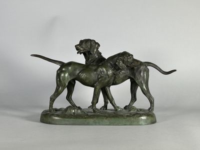 une statue en bronze représentant deux chiens, posée sur un socle en marbre