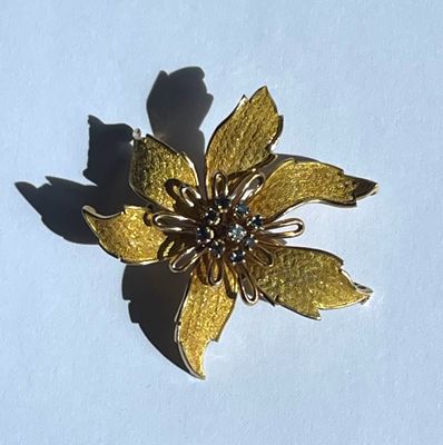 une broche en forme de fleur dorée sur un fond blanc