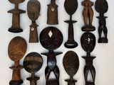 Plusieurs figurines africaines en bois sont disposées sur une surface blanche