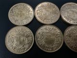 six different british coins sitting on top of a black surface