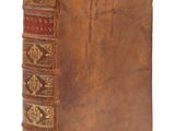 un vieux livre à la couverture brune posé sur une surface blanche