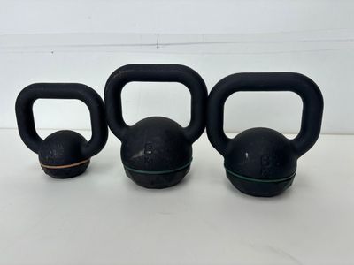 three black kettle weights sitting on top of a white table