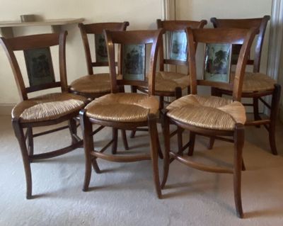 four wooden chairs with wicker seats in the middle of a room