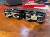 a toy train sitting on a table with a laptop in the background