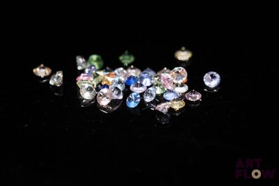a close up of a bunch of different colored diamonds on a black surface