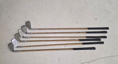 quatre clubs de golf sont alignés en rang sur le sol