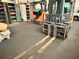 un chariot élévateur dans un entrepôt, avec des palettes au premier plan