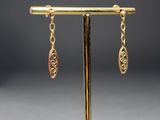 a pair of gold earrings on a stand