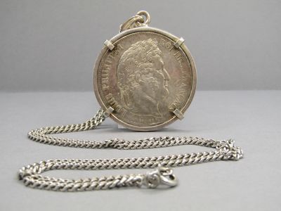 une pièce d'argent entourée d'une chaîne, posée sur une table