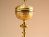 a golden cup with a cross on top sitting on a table