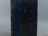 an old book sitting on top of a white table next to a blue book