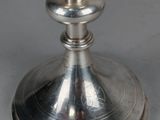 a silver cup on a silver plate on a table