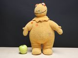 a stuffed animal that is standing next to an apple