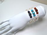 a white mannequin hand holding a bracelet with multi colored beads