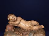 an old statue of a man laying on a rock on a blue background