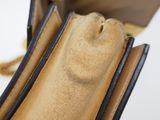 a brown purse with a black handle on a white surface