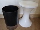 a black and white trash can next to a white stool