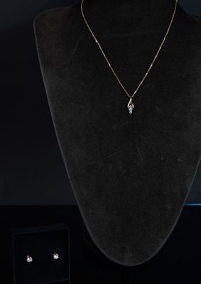 un collier et des boucles d'oreilles posés sur un mannequin devant un fond noir