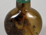 a small glass bottle with a green lid on a white surface