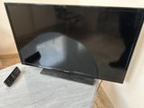 un téléviseur avec sa télécommande posé sur une table devant un mur