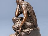 an image of a bronze statue of a man sitting on a rock