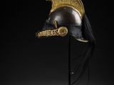 a gold helmet with a red feather on top of it