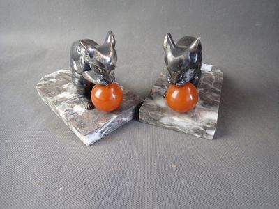 pair of silver cat figurines with orange ball on marble bases