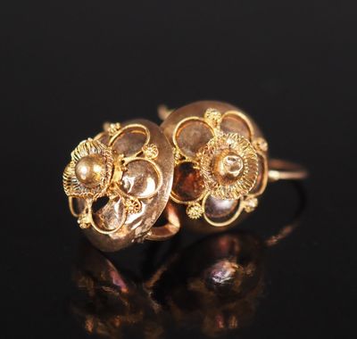 un gros plan sur une paire de boucles d'oreilles en or posées sur une surface noire