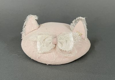 a small pink cat with a bow on it ' s head