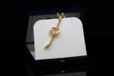 a gold brooch in a black box on a black surface