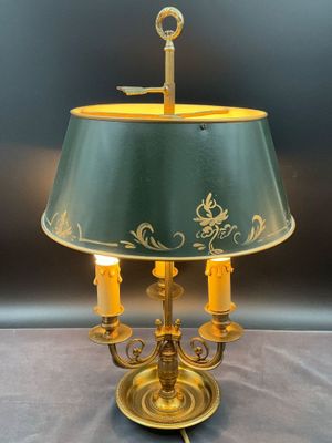 une lampe posée sur une table, avec un abat-jour vert