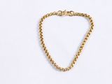 a close up of a gold chain bracelet on a white surface