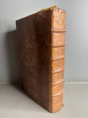 an old brown book sitting on top of a table next to a wall