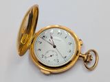 a gold pocket watch sitting on a white surface
