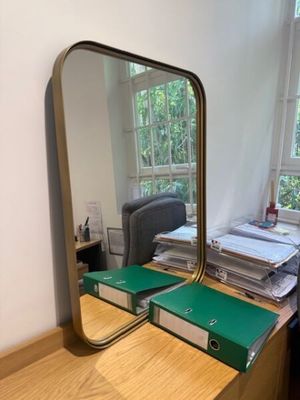 un bureau avec un miroir et une chaise devant une fenêtre
