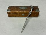 a small wooden box with a pair of scissors in it