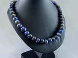 a black mannequin with a blue beaded necklace on it