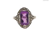 gros plan d'une bague avec une pierre violette entourée de diamants