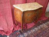 une petite table au plateau en marbre, devant un rideau rouge